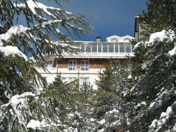 Fachada real del Hotel Reino Nevado entre árboles nevados