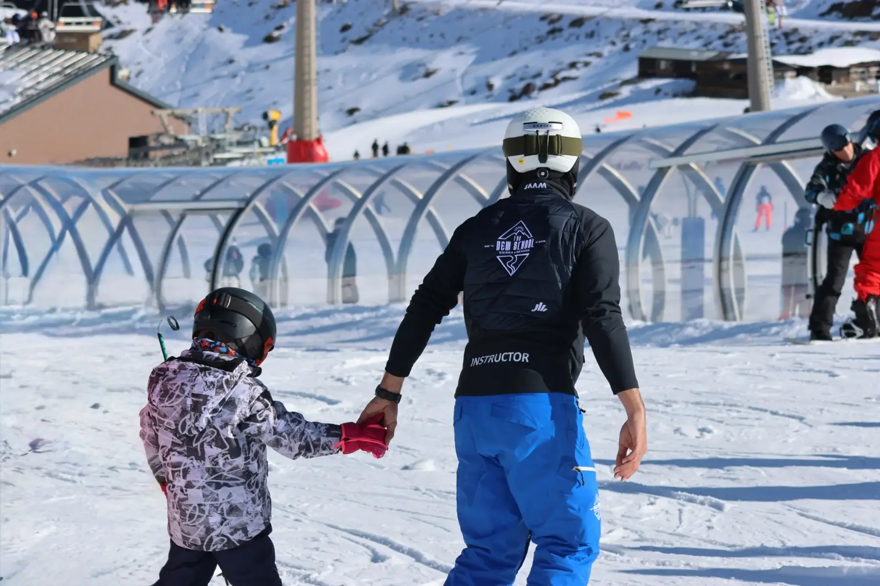 Profesor de The New School cogiendo de la mano a un niño en la nieve